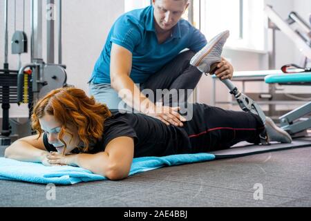 Personal trainer Unterstützung Frau mit Behinderungen in Ihr Training. Sport Reha-zentrum mit Physiotherapeuten und Patienten gemeinsam für Hea Stockfoto