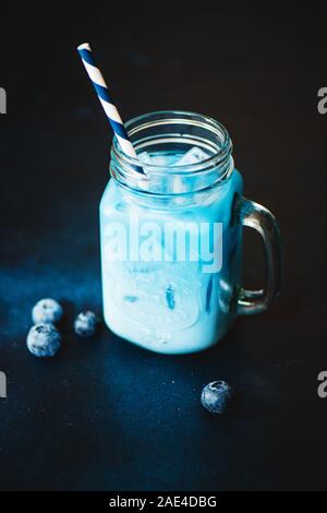 Trendy blue Matcha Drink mit Blueberry auf dunklem Hintergrund. Stockfoto