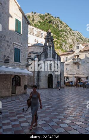 St. Luke's Kirche (Crkva Sv Lukas) in der gleichnamigen Platz (Trg Sv Lukas), Kotor, Montenegro: Eine Frau geht über den Platz Stockfoto