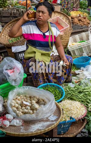 Eine burmesische Frau auf ein Handy verkauft frisches Gemüse und Betelnuss in der Eisenbahn von Mandalay, Myanmar (Birma) Stockfoto