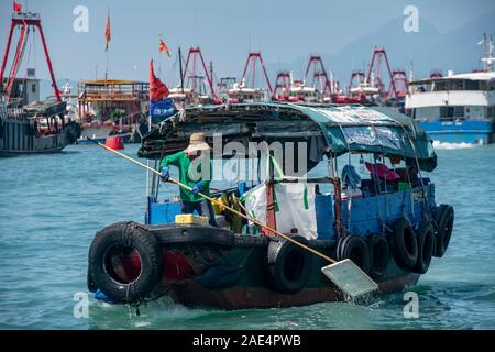 Eine Regierung Arbeiter reinigt das Wasser von Hong Kong Island Aberdeen Hafen mit einem Net, Kommissionierung bis Müll, Müll und andere Verschmutzungen. Stockfoto