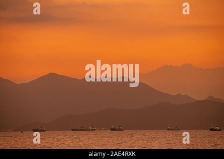 Sonnenuntergang von Lamma Island in Hongkong als lokale Schiffe in Richtung Hafen Aberdeen Stockfoto