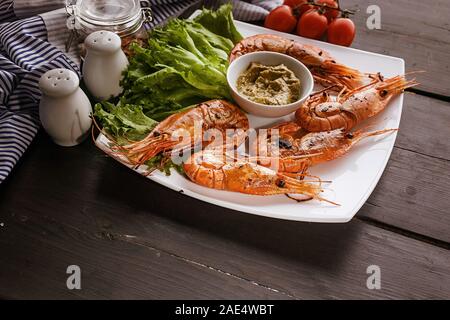 Close-up gegrillte Garnelen mit Knoblauch und Zitronen auf einem weißen Teller mit Salat Stockfoto