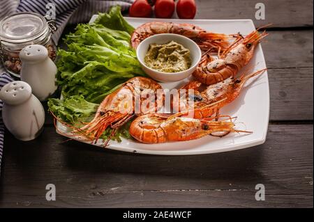 Close-up Gegrillte Garnelen mit Knoblauch und Zitronen auf einem weißen Teller mit Salat Stockfoto