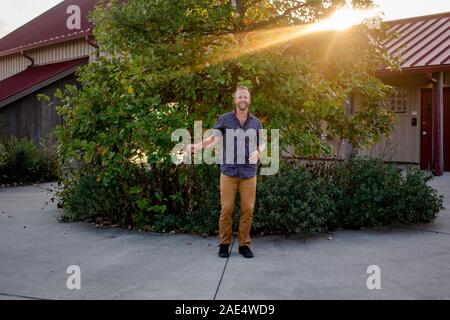 Ein stolzer Mann lächelt, vor seinem Haus bei Sonnenuntergang im Sommer Stockfoto