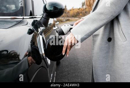 Woman's Hand Aufstecken eines Ladegeräts an ihr Elektroauto Stockfoto