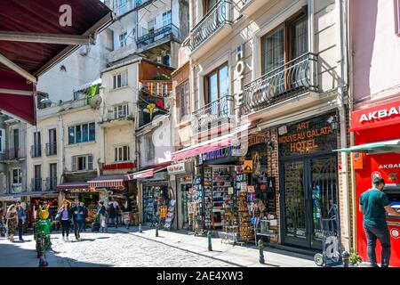 Touristen vorbei an bunt- und Souvenirgeschäfte und Cafés an einem langen Sommertag in der Galata Stadtteil Karakoy Istanbul, Türkei Stockfoto