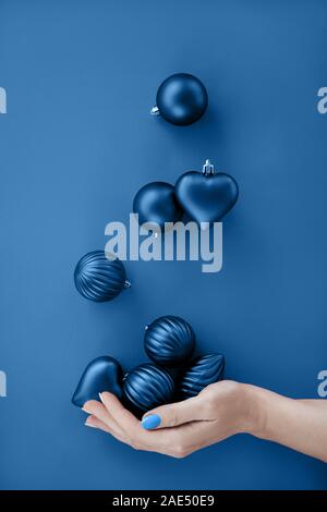Weibliche Hand jonglieren Blau Weihnachten runden Kugeln und Herzen Form. Stockfoto