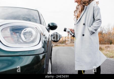 Frauen lächelnd in die eine elektrische Auto auf einer Landstraße Stockfoto