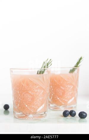 Ein rosa Cocktail mit einem Zweig Rosmarin Stockfoto