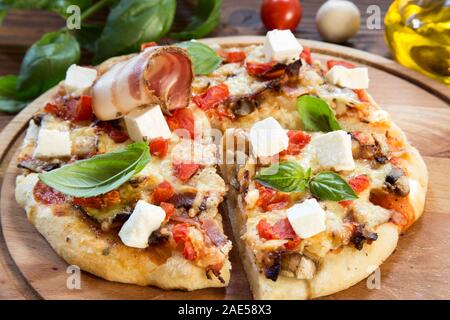 Hausgemachte Pizza im Landhausstil serviert auf einem Tisch Stockfoto