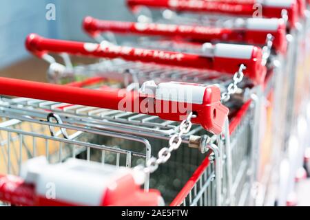 Reihe von Shopping Carts mit roten Griffe am Abend verschwommenen Hintergrund in der Nähe der Eingang der Supermarkt im Winter Stockfoto