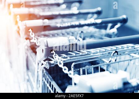 Reihe von Shopping Carts mit roten Griffe am Abend verschwommenen Hintergrund in der Nähe der Eingang der Supermarkt im Winter Stockfoto