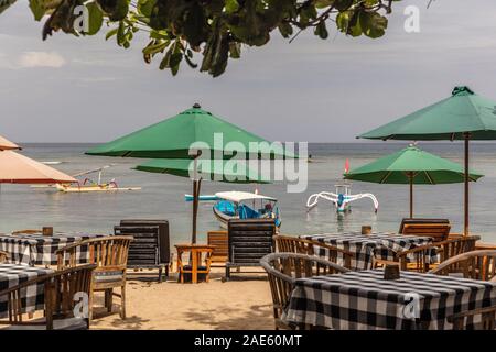 Sonnenschirme und Tische in einem Strandcafé im Pantai Sanur, Bali, Indonesien. Stockfoto