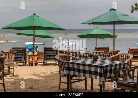 Sonnenschirme und Tische in einem Strandcafé im Pantai Sanur, Bali, Indonesien. Stockfoto