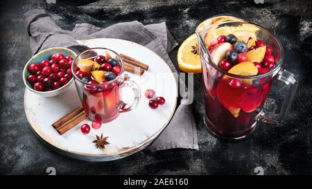 Winter Weihnachten heißen Getränk. Cranberry und Orange winter Sangria oder Glühwein oder Glühwein auf dunklem Hintergrund. Weihnachten Konzept Stockfoto