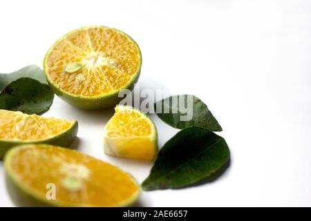 Gruppe von frischen grünen Zitrusfrüchten und ihre Blätter, die orange Farbe innen und Slice in unterschiedlicher Größe und in weisser Farbe einstellen Stockfoto
