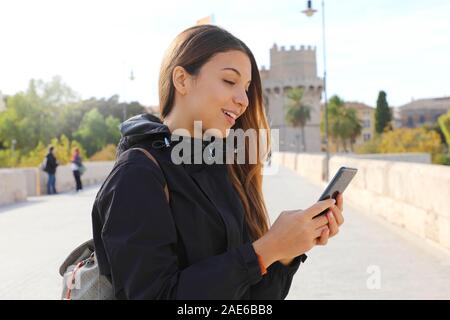 Nahaufnahme, Porträt einer jungen Frau, die gerne zu Fuß in der Stadt senden von SMS auf dem Telefon im Herbst oder im Winter. Stockfoto