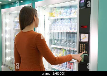 Junge reisende Frau wählen Sie einen Snack oder ein Getränk am Automaten im Flughafen. Automaten mit Mädchen. Stockfoto