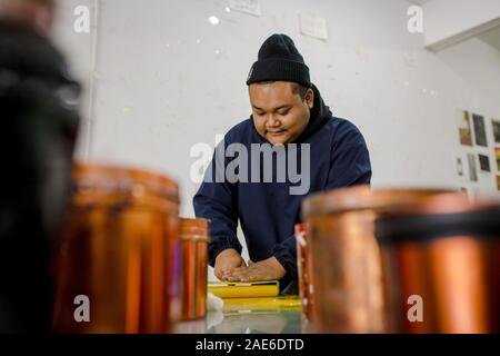 Pu'er, der chinesischen Provinz Yunnan. 5 Dez, 2019. Student Zhong Ping verschmierte Tinte auf der Holzschnitt Studio von Pu'er-Universität in Pu'er-Stadt, im Südwesten der chinesischen Provinz Yunnan, Dez. 5, 2019. Die Jueban Holzschnitt ist eine Art der Holzschnitzerei Technik aus der Stadt Pu'er in den 1980er Jahren. Credit: Hu Chao/Xinhua/Alamy leben Nachrichten Stockfoto