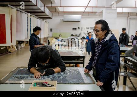 Pu'er, der chinesischen Provinz Yunnan. 5 Dez, 2019. Student Chen Duo (L) von kunst-Institut macht Jueban Holzschnitt Malerei unter der Leitung eines Lehrers an der Holzschnitt Studio von Pu'er-Universität in Pu'er-Stadt, im Südwesten der chinesischen Provinz Yunnan, Dez. 5, 2019. Die Jueban Holzschnitt ist eine Art der Holzschnitzerei Technik aus der Stadt Pu'er in den 1980er Jahren. Credit: Hu Chao/Xinhua/Alamy leben Nachrichten Stockfoto