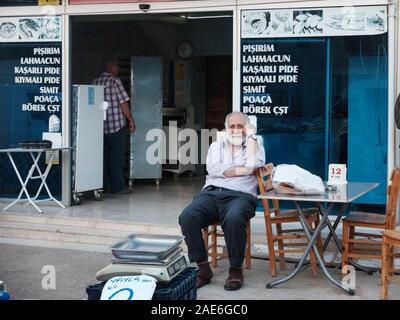 Tasucu, Provinz Mersin, Türkei - Mai 2019. Alte grauhaarige bärtiger Mann sitzt auf einem Stuhl in der Nähe des Cafe am türkischen Markt. Stockfoto