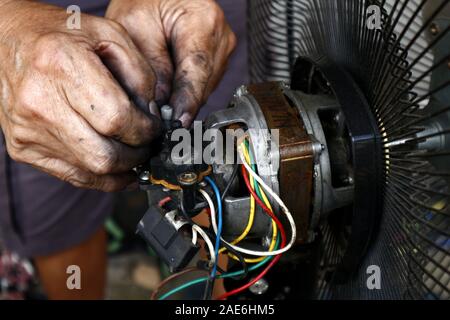 Nahaufnahme Foto von einem Paar Hände zur Festsetzung der Motor von einem elektrischen Ventilator Stockfoto