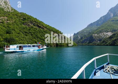 Koman, Albanien, dem 7. Juli 2019: ein Tourist Boot überholt die Autofähre auf Komani See in den Dinarischen Alpen von Albanien Stockfoto