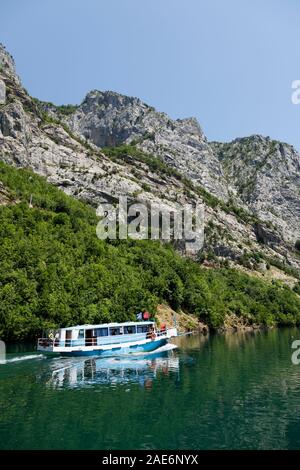 Koman, Albanien, dem 7. Juli 2019: ein Tourist Boot überholt die Autofähre auf Komani See in den Dinarischen Alpen von Albanien Stockfoto