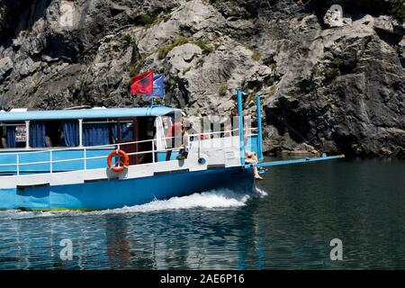 Koman, Albanien, dem 7. Juli 2019: ein Tourist Boot überholt die Autofähre auf Komani See in den Dinarischen Alpen von Albanien Stockfoto