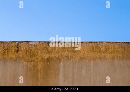 Feuchtigkeit an der Zementwand außerhalb des Gebäudes, blauer Himmel Hintergrund Stockfoto