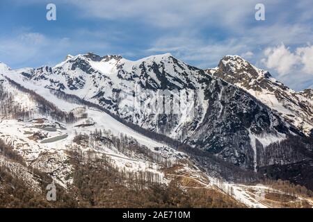 Blooming cherry tree mit Blick auf die schneebedeckten Berge, die im Frühjahr an einem klaren Tag in Sochi, Russland. Stockfoto