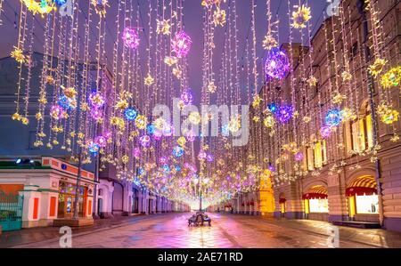 Moskau, Russland. Goldener, farbenfroher Regen mit Weihnachtsdekorationen, der am Himmel hängt, in der Nikolskaja-Straße neben DEM KAUGUMMI in der Hauptstadt. Wunderschöne Lichter. Stockfoto