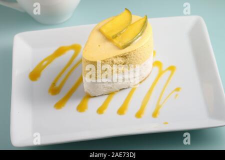 Mango und Sauerrahm Dessert gekrönt mit Schichten von Mango auf einer Platte dekoriert mit Mango Püree Stockfoto