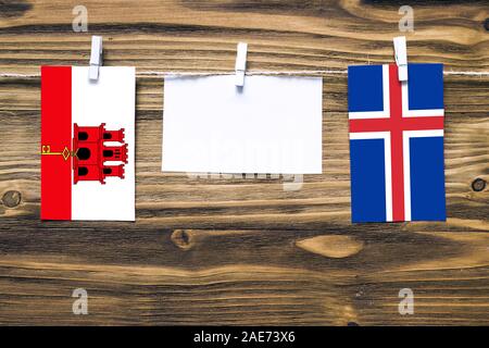 Hängenden Flaggen von Gibraltar Island und Seil mit wäscheklammer mit Kopie Raum befestigt auf weißem Papier auf Holz- Hintergrund. diplomatischen Beziehungen Stockfoto