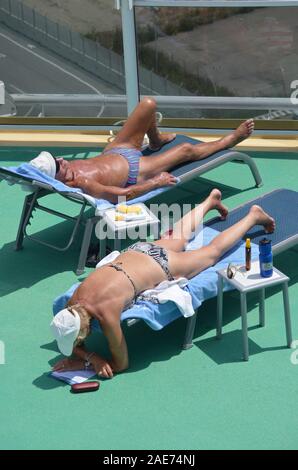 Ein älteres Paar in ihren Badeanzug entspannen Sie an Deck der Norwegian Epic Cruise Schiff angedockt war. Stockfoto