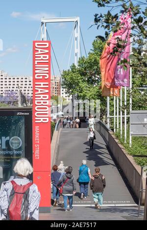 Menschen zu Fuß über einen schmalen Fußgängerbrücke, die links Sydneys CBD zum Darling Harbour und Darling Quartal Unterhaltungs- und Restaurantviertel Stockfoto