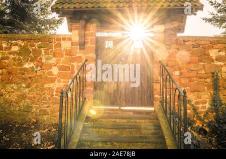 Steinmauer mit Holz alte Tür und Sonnenstrahlen durchscheinen. Konzept von Heaven's Gate Stockfoto