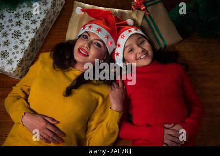 Porträt einer Mutter und Tochter auf dem Boden neben der Weihnachtsgeschenke. Stockfoto