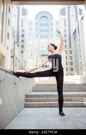 Flexible junge Frau in Schwarz mit erhobener Hand posieren sportssuit Stockfoto