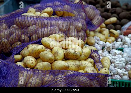 Gemüse der Saison werden in Kartons im Lebensmittelgeschäft gestapelt. In der Nähe liegen große Knollen Kartoffeln und Knoblauch. Ökologische Lebensmittel. Stockfoto