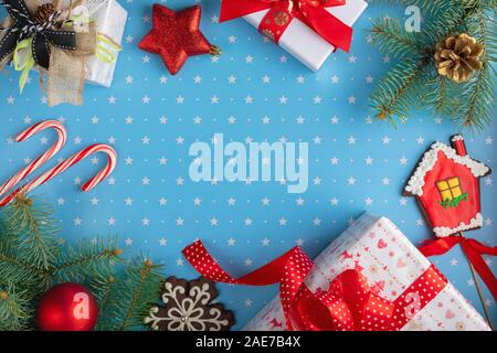 Weihnachten Komposition. Geschenke, Tannenbaum Äste, Tannenzapfen, Schneeflocke Lebkuchen, Lebkuchen, Bonbons und Kugeln auf blauem Hintergrund Stockfoto