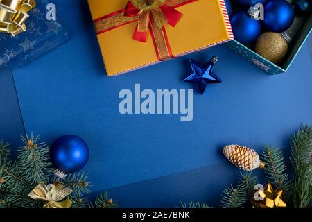 Weihnachten Zusammensetzung mit Dekorationen, Geschenkboxen Flitter und Zweige der Tanne auf klassischen blauen Hintergrund. Weihnachten Hintergrund Stockfoto