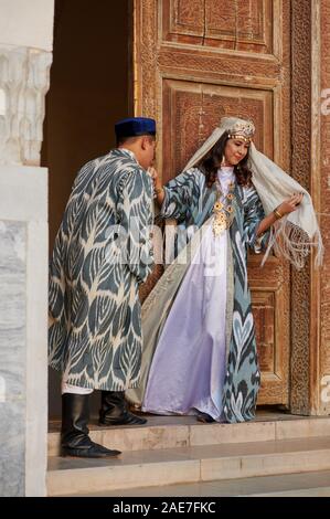 Brautpaar in traditioneller Kleidung vor der berühmten Registan Platz, Samarkand, Usbekistan, in Zentralasien posing Stockfoto