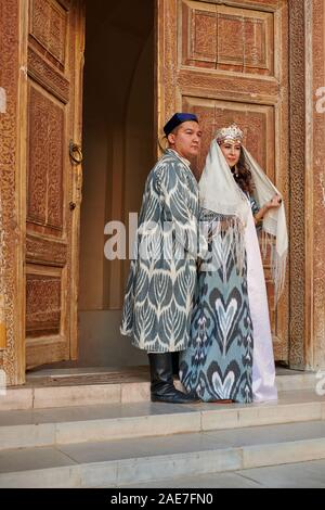 Brautpaar in traditioneller Kleidung vor der berühmten Registan Platz, Samarkand, Usbekistan, in Zentralasien posing Stockfoto