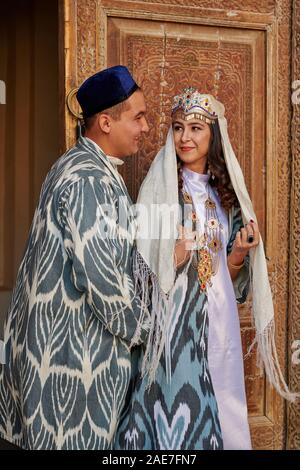 Brautpaar in traditioneller Kleidung vor der berühmten Registan Platz, Samarkand, Usbekistan, in Zentralasien posing Stockfoto