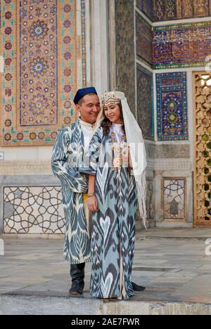 Brautpaar in traditioneller Kleidung vor der berühmten Registan Platz, Samarkand, Usbekistan, in Zentralasien posing Stockfoto