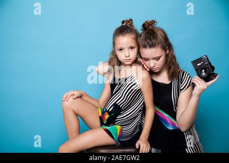 Zwei modischen Schwestern Mädchen mit einer Kamera auf einem blauen Hintergrund Stockfoto