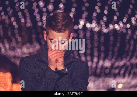 Close up Portrait von stattlichen Mann, der versucht, ihm seine Hände im Winter nachts zu warm in der Stadt Straße. Stockfoto