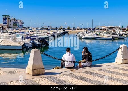 Junges Paar, das im Freien ein romantisches Mittagessen genießt, sitzt auf dem Dock am Yachthafen von Faro, Ostalgarve Portugal. Stockfoto